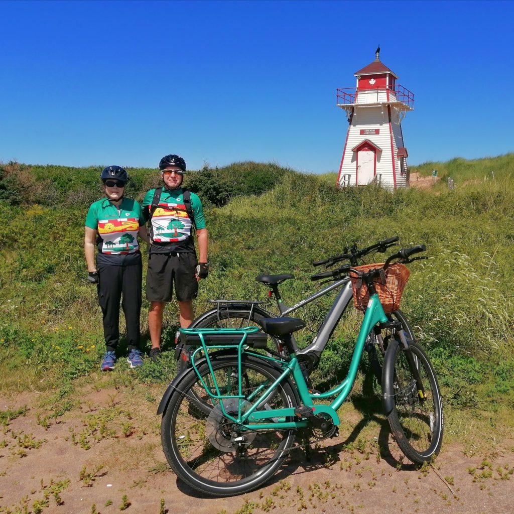 Two cyclists with their bicycles beside Covehead Lighthouse on Prince Edward Island