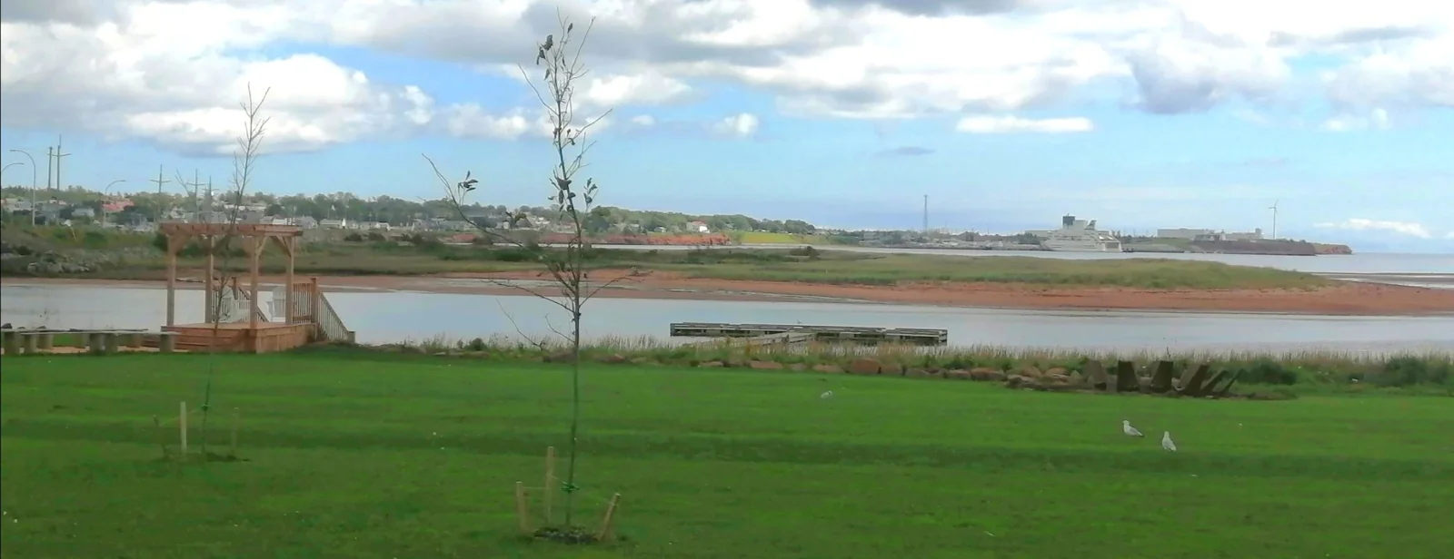 Water and green countryside under a cloudy sky