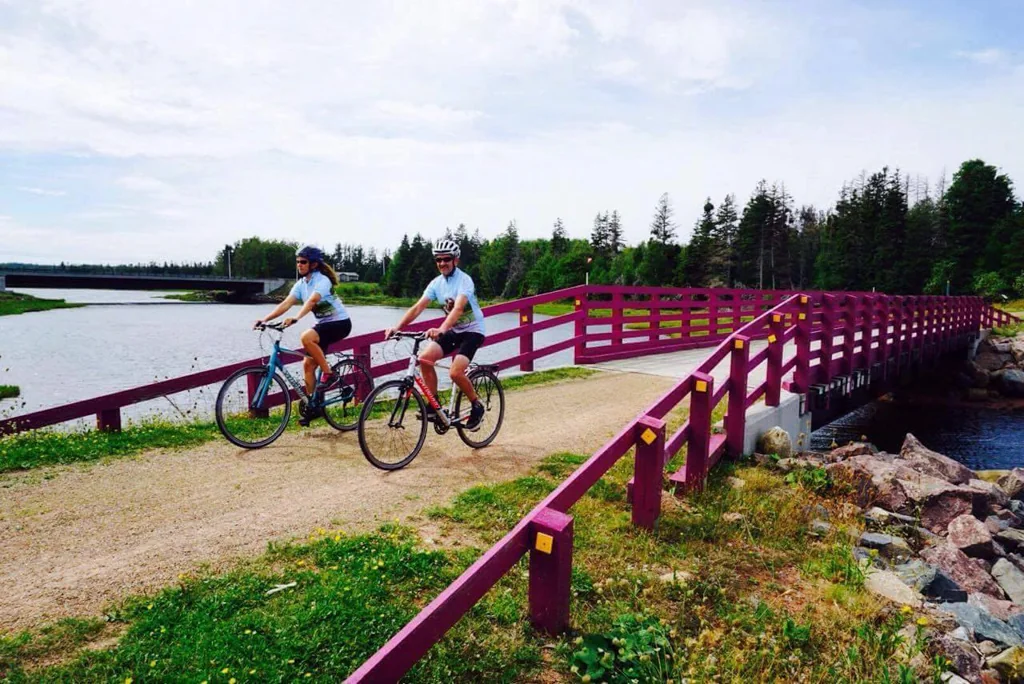 A cyclist beside a pink bridge overlooking the water
